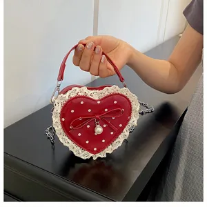 Detail shot of the red heart-shaped polka dot bag with white lace trim, bow and pearl pendant.