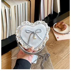 Silver heart-shaped kids crossbody bag with cute lace trim, bow and pearl pendant detail.