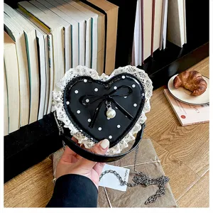 Cute heart-shaped polka dot kids crossbody bag with lace trim, bow and pearl pendant details.