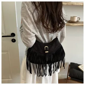 Detailed view of black suede fringe shoulder bag with metal buckle, bohemian retro style.