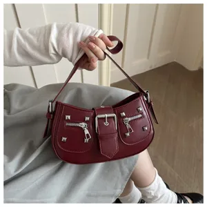 Dettaglio borsa a mezzaluna bordeaux con fibbia in metallo e tasche con cerniera chic.