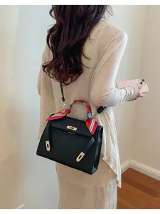 Vista detallada de elegante bolso de hombro negro para mujer con bufanda y herrajes.