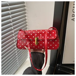 Red polka dot patent leather underarm bag detail, showcasing texture and vintage style.