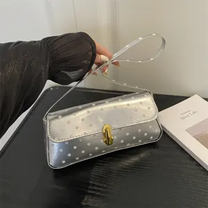 Silver polka dot shoulder baguette bag for women, chic metallic handbag with secure gold lock.
