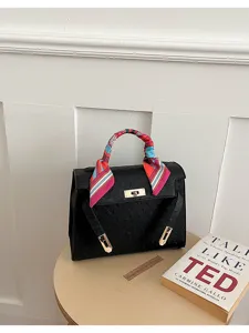 Bolso de mano de cuero negro con pañuelo colorido y cerradura metálica, bolso elegante.