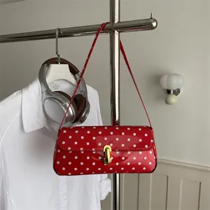 Red polka dot patent leather shoulder bag for women, chic baguette handbag for daily commute.