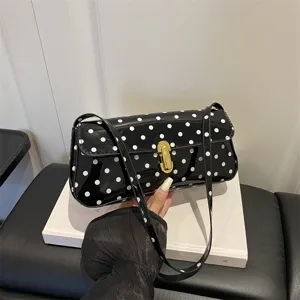 Chic black and white polka dot patent leather shoulder bag with gold clasp for women.