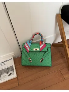 Detalle de bolso cruzado de cuero con textura de avestruz verde, estilo elegante.