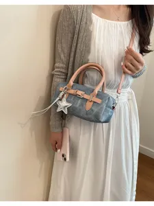 Detail view of stylish denim barrel shoulder bag with pink straps and star charm pendant.