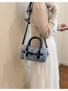 Detail view of a chic grey barrel shoulder bag with contrast blue straps and silver charm.