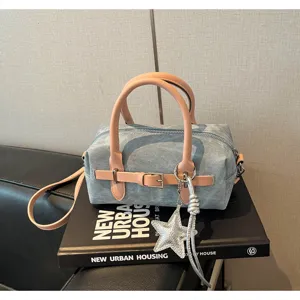 Detailed view of the stylish blue denim barrel bag with pink handles and silver star charm.