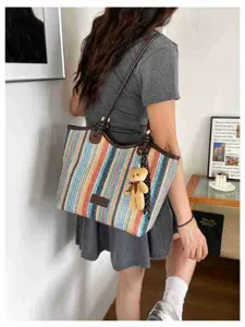 Detailed view of colorful woven canvas tote bag with brown leather handles and cute bear charm.