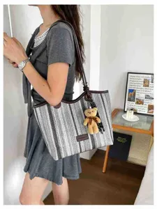 Close-up detail of the stylish color-block woven canvas tote bag with cute bear pendant.