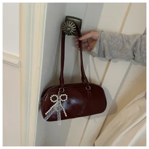 Wine red patent leather shoulder bag with elegant pearl bow pendant for women daily commuting.