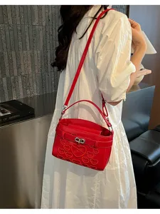 Red leather shoulder crossbody bag with elegant heart embroidery and metal lock closure.