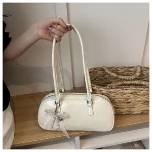 Elegant white shoulder bag detail showing premium texture, leather handle and chic pearl bow.