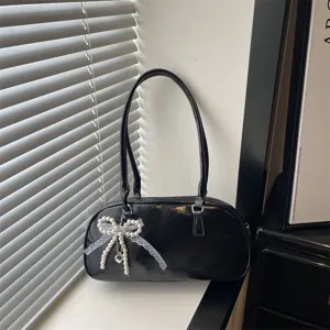 Black patent leather shoulder bag for women, chic pillow handbag with pearl bow charm.