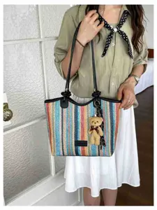 Detail view of the colorful woven tote bag featuring a cute bear pendant and handles.
