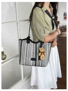 Detail view of the stylish striped straw tote bag, featuring comfortable handles and cute bear charm.