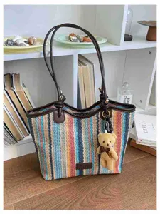Detailed view of the colorful striped straw tote bag with brown leather straps and cute bear.