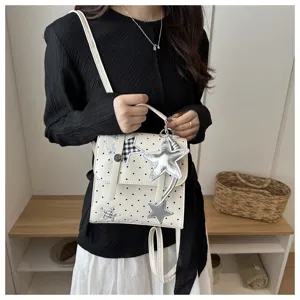 Detail view of white polka dot college style backpack with star pendants and shoulder straps.