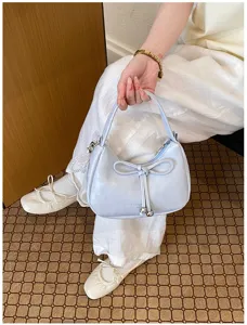 Vista di dettaglio della elegante borsa a spalla azzurra con grazioso fiocco e perla.