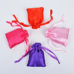 Detailed view of multi-colored satin drawstring pouches in red, pink, and purple.