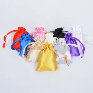Assortment of colorful satin drawstring gift pouches with silky texture on white background