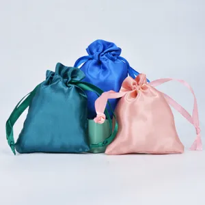Close-up detail of silky satin drawstring pouches in teal, royal blue, and pink colors