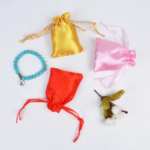 Detail view of smooth satin drawstring gift pouches in vibrant red, pink, and yellow colors