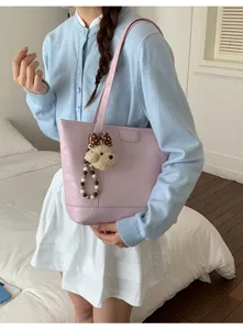 Detailed view of the pink PU leather shoulder tote bag featuring a cute bear plush charm.