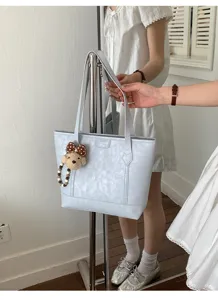 Soft PU leather tote bag for women, large capacity casual single shoulder handbag with cute bear pendant.