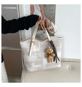 Detailed close-up view of large capacity casual tote shoulder bag with cute bear pendant.