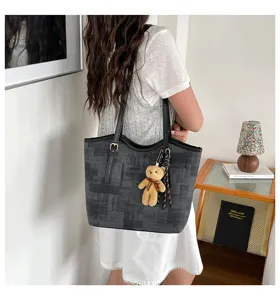 Detailed view of large capacity grey tote shoulder bag with cute bear pendant in indoor scene.
