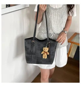 Detailed shot of trendy grey patterned tote bag with cute bear charm worn by model.