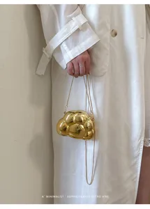 Vue de détail d'un sac bandoulière métallique doré chic en forme de nuage avec chaîne.