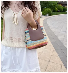 Detailed close-up of the colorful striped straw handbag with chic brown leather handles.