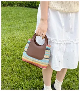 Close-up of a colorful straw woven handbag with brown round handle for summer outfit style.