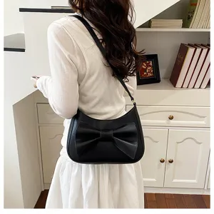 Close-up detail of a chic black underarm shoulder bag featuring an elegant oversized bow.