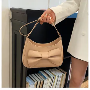 Beige shoulder bag for women with a chic large bow, stylish minimalist underarm design.