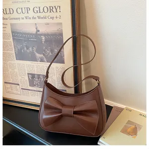 Detailed shot of a chic brown women shoulder bag featuring a stylish front bow and strap.