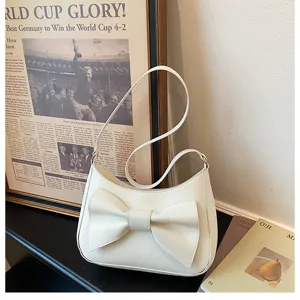 Close-up detail of the elegant white shoulder bag featuring a chic bow in a modern stylish setup.