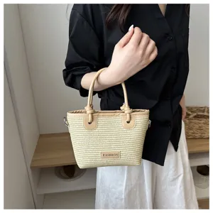 Woven straw bucket bag featuring stylish leather knot handle, ideal for summer beach styling.