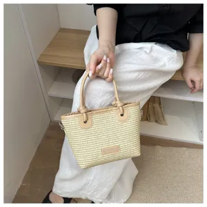 Chic straw bucket handbag with knotted handles for women, stylish summer beach bag.