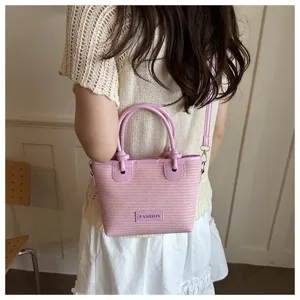 Pink woven bucket bag with top handle and strap, stylish beach straw handbag for women.