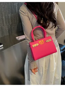 Detail view of stylish pink top-handle shoulder bag with chic metal hardware and gold accents.