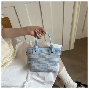 Detailed shot of the light blue woven bucket bag with stylish knot handles and front label.