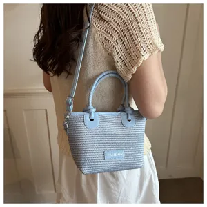 Detail view of light blue woven bucket bag with shoulder strap and stylish knot handles.