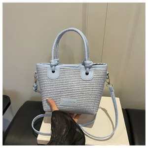Light blue woven bucket bag with top handle and crossbody strap, stylish straw handbag for summer.