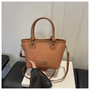Stylish straw woven bucket bag with top handle and crossbody strap, perfect for beach use.